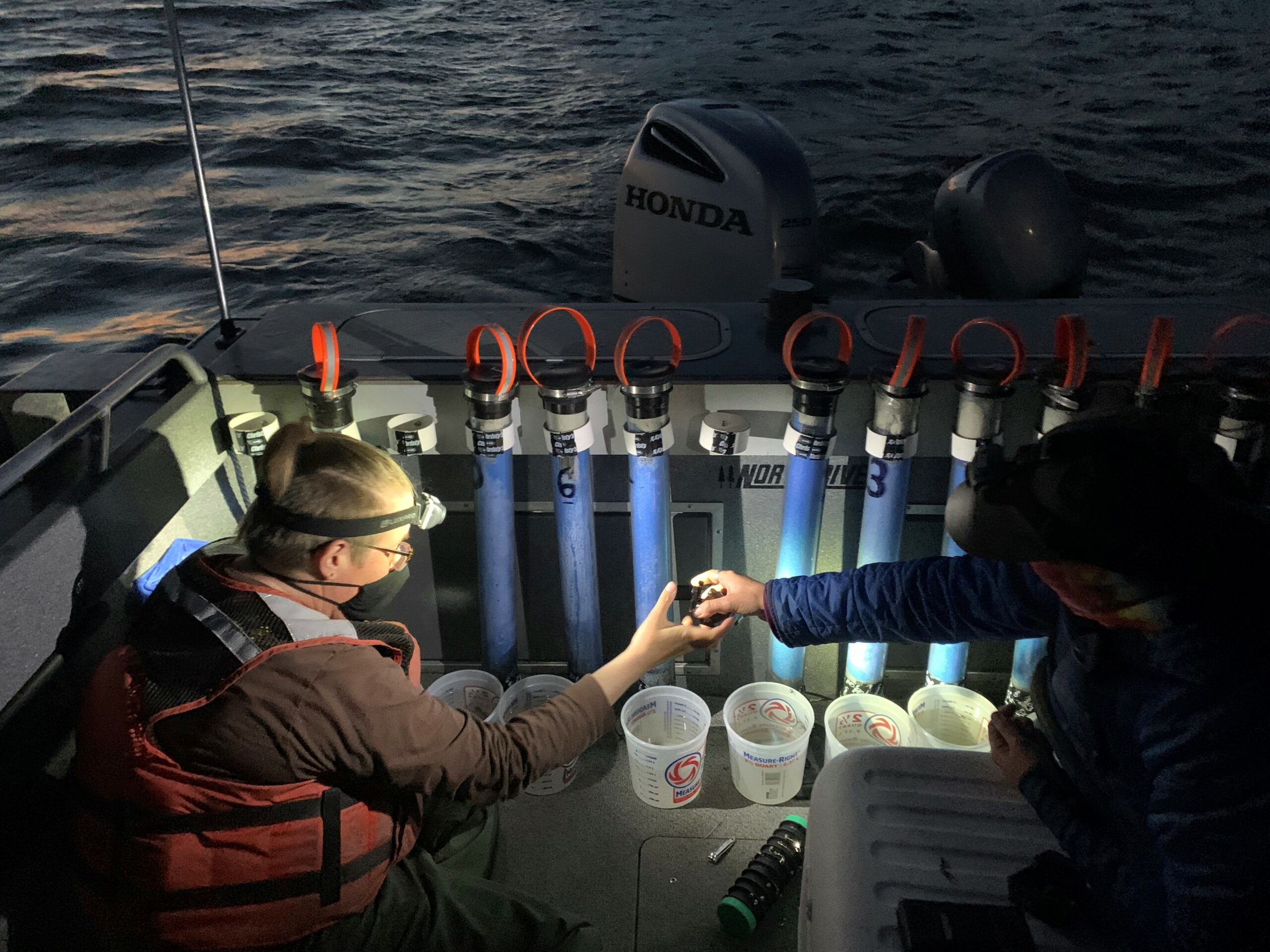 PERs Units being prepared for use on a boat at night by two scientists.